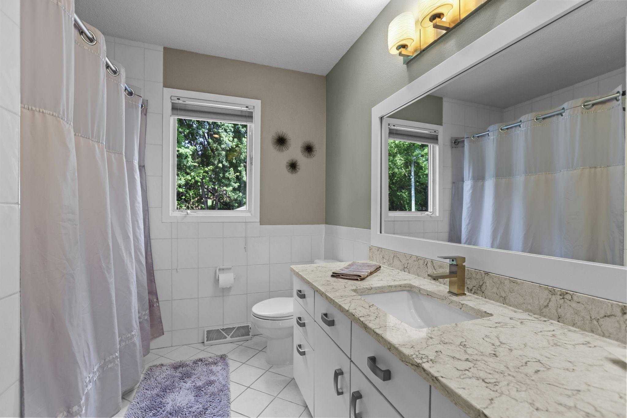 Full bathroom with tile floors, granite countertop