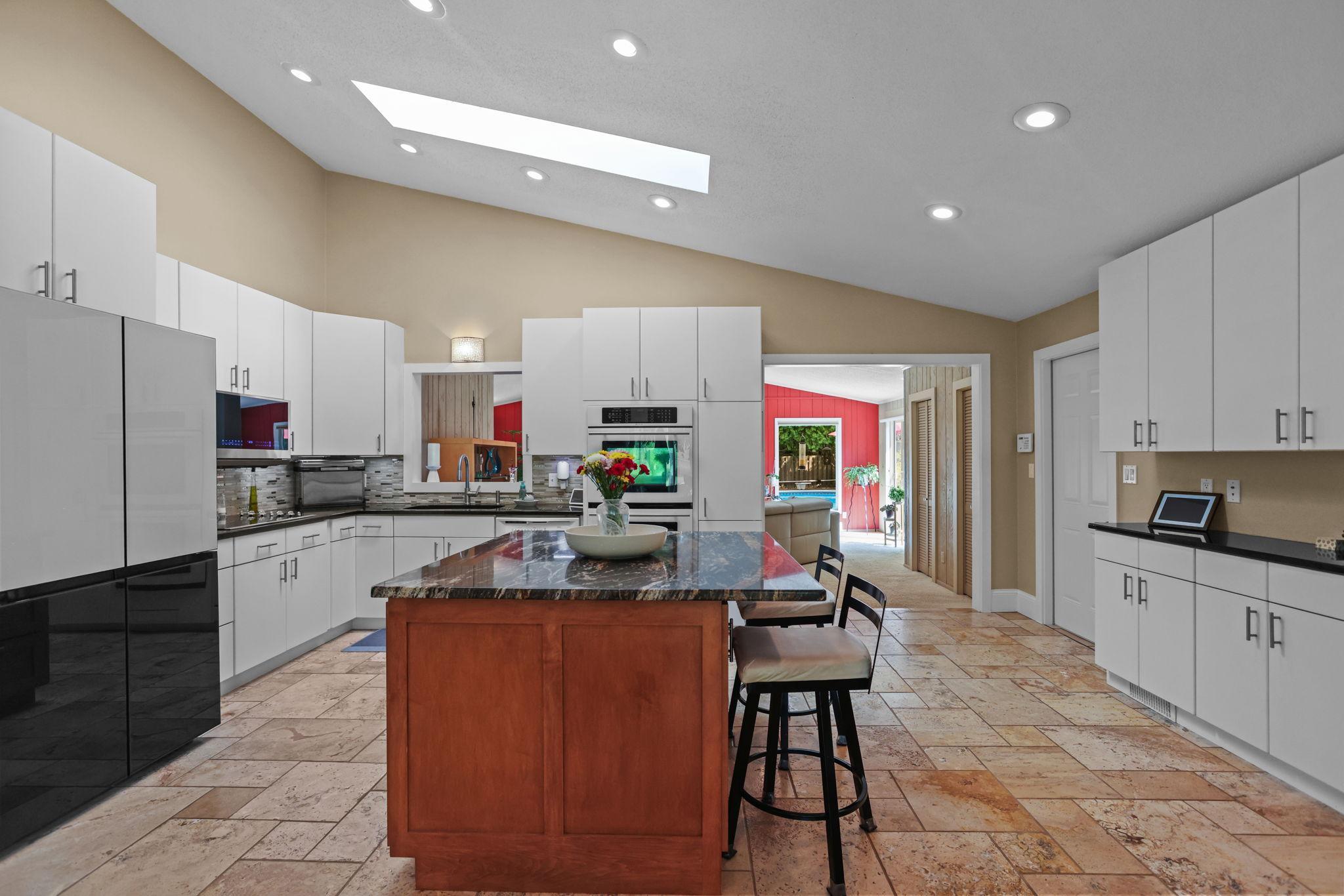 Updated appliances, separate wall ovens, tile floor, large center island, vaulted ceiling, attached garage