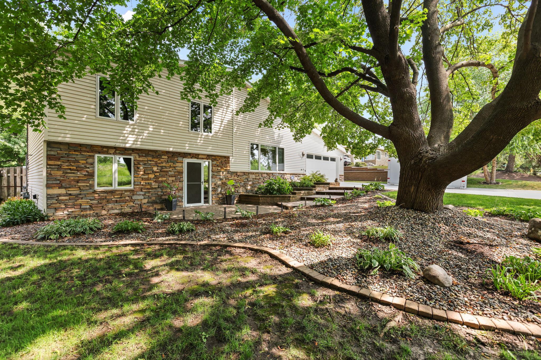 Street view front of home, in-ground irrigation, custom landscaping, perennials, paver and stone accents