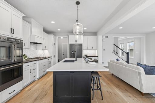 This oversized island is a showstopper, offering sleek white countertops, generous cabinet storage, and a breakfast bar ideal for quick morning meals or gathering with guests while you cook.