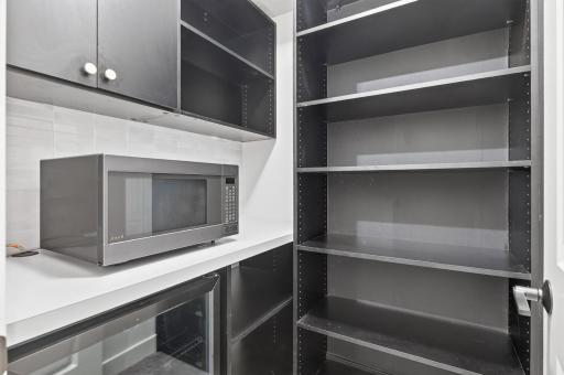 Butler pantry with fridge, microwave and shelving.