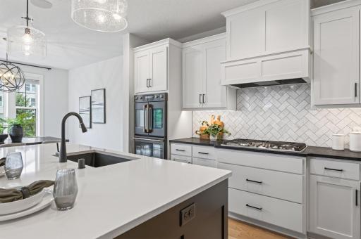 This cooktop nook has it all: crisp white enameled counters, a gas cooktop for precision cooking, convenient pull-out drawers for pots and pans, an eye-catching tile backsplash, and the double oven within easy reach.