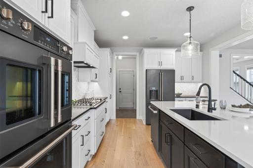 High-end appliances elevate this stunning kitchen: double wall ovens, a 36" gas cooktop for precision cooking, and a sleek black French door fridge with water dispenser for everyday convenience.