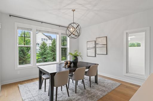 Oversized windows frame beautiful views of the yard while filling the dining room with warm, natural light; perfect for enjoying meals in a bright, airy setting.
