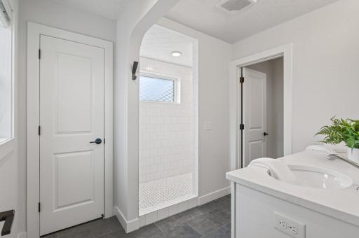 Primary bathroom features a linen closet, dual sinks, a tiled walk-in shower, and a private toilet.