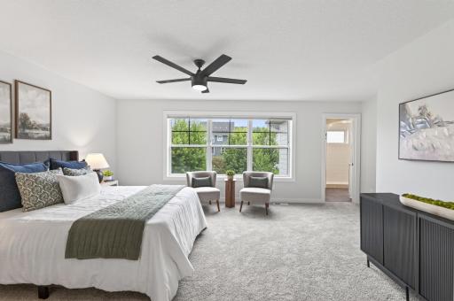 The primary bedroom's oversized windows enhance the room's spacious feel while bringing in an abundance of natural light.