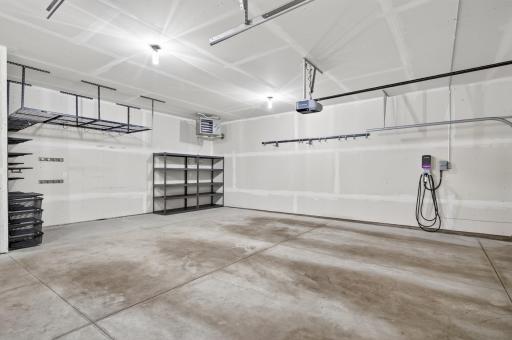A true car enthusiast's dream; this insulated and heated 3-car garage offers extra-tall ceilings, an included EV charger, dual garage door openers, and included metal storage racks.