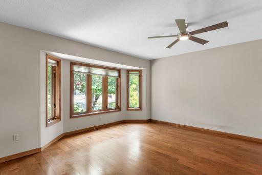 The living room is filled with natural light and features a front-facing bay window before opening into the kitchen.