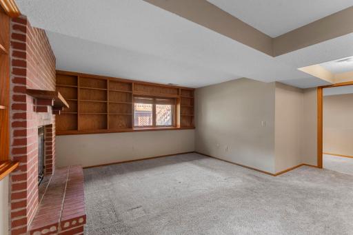 The spacious family room is centered around a brick wood-burning fireplace and surrounded by built-in shelving.
