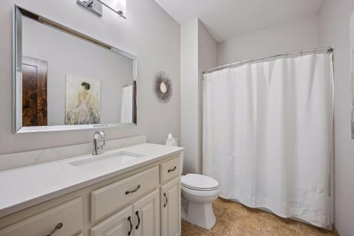 The main-level full bath features an extended vanity, a neutral color palette, and a tub/shower combination.