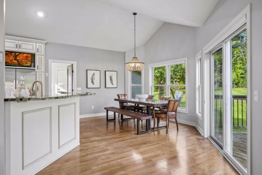 White oak hardwood floors extend into the informal dining area, where a sliding door provides easy access to the deck.