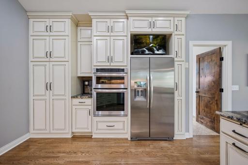 Floor-to-ceiling cabinetry surrounds the refrigerator and built-in oven, maximizing storage and function.