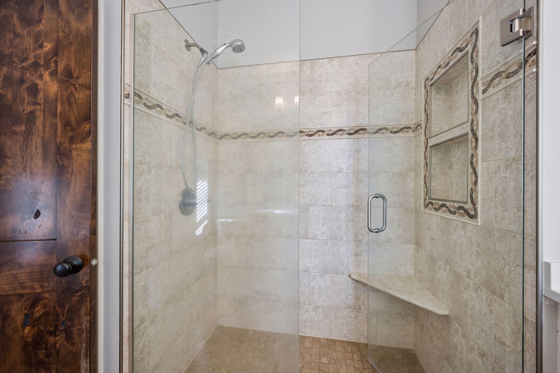A closer look at the spacious tiled shower with a glass enclosure and built-in niche.
