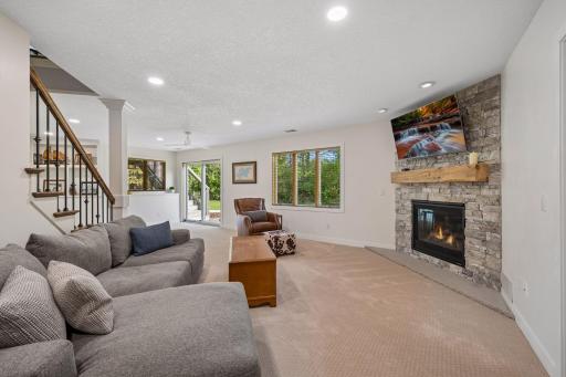 The recessed lighting and stone fireplace create a bright, inviting gathering space.