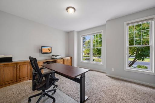 Two front-facing windows bring natural light into the second main-level bedroom, currently used as an office.