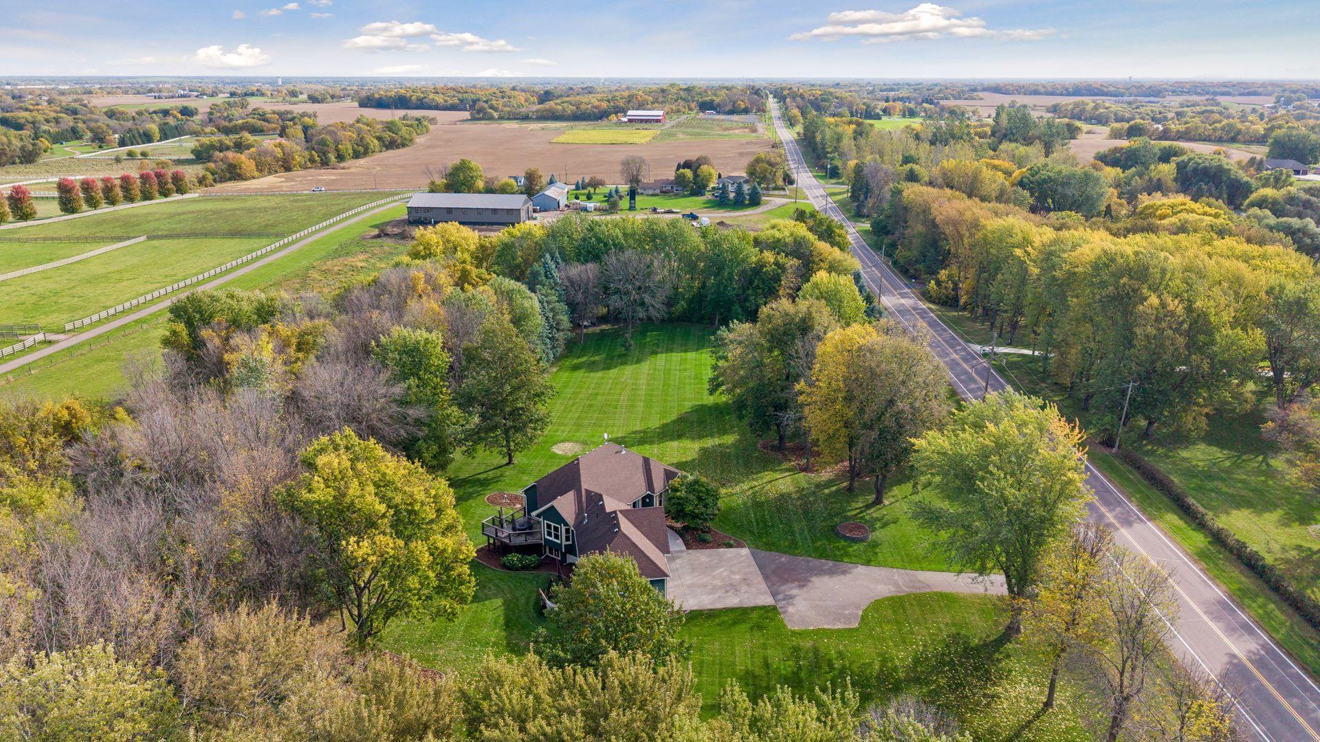 An aerial view showcases the home’s private setting, generous yard, and large driveway.