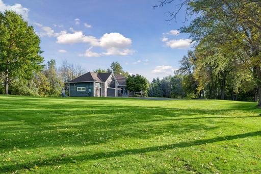 A picturesque view from the front side yard showcases the homeâs private setting and generous surrounding acreage.
