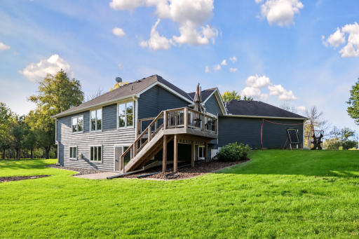The rear exterior highlights the deck, walkout lower level, and expansive lawn.