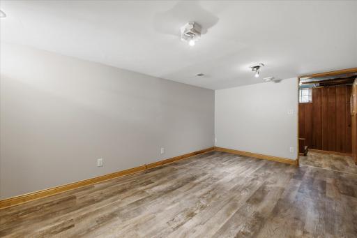 This lower-level area offers additional flexible space with durable flooring, neutral finishes, built-in shelving, and convenient access to the home's utility and storage areas.