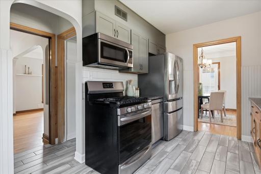 The kitchen offers generous cabinetry and counter space, stainless steel appliances, a tile backsplash, and durable tile flooring, creating a functional layout for everyday cooking.