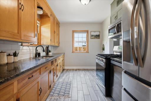 The updated kitchen combines warm wood cabinetry with granite countertops, a tile backsplash, and modern stainless steel appliances for a practical and inviting cooking space.