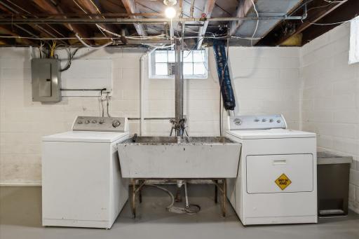 The basement laundry area includes a washer and dryer, utility sink, concrete flooring, and convenient access to the home's mechanical systems.