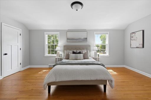 The spacious primary bedroom features hardwood floors, two large windows, neutral finishes, and ample room for comfortable furnishings, creating a bright and relaxing retreat.