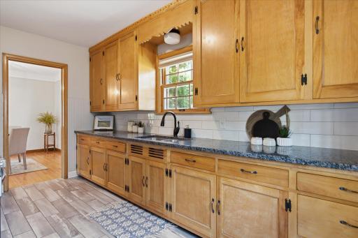 Beautiful wood cabinetry provides abundant storage throughout the kitchen, complemented by granite countertops, a subway tile backsplash, and classic detailing that preserves the home's character.