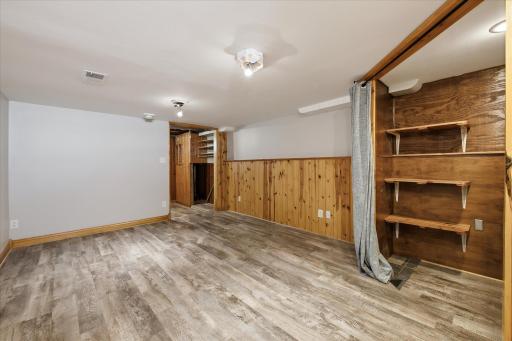 A second view of the finished lower level highlights the generous floor space, built-in shelving, wood accents, and flexible layout suitable for a family room, office, or hobby area.