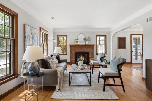 The bright living room features beautiful hardwood floors, generous windows, and classic wood trim, creating a comfortable gathering space filled with natural light and timeless character.