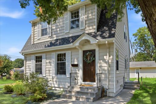 The front exterior highlights the home's classic Colonial character, well-maintained siding, charming architectural details, and welcoming entry surrounded by mature landscaping.