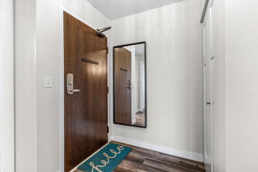 Entry foyer featuring warm wood doors, a full-length mirror, and direct access to the open living area.