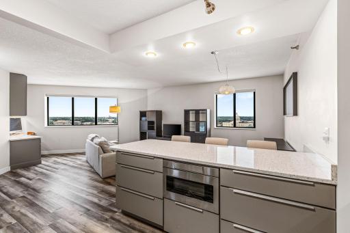 Bright open-concept kitchen and living area with modern finishes, generous counter space, and expansive city views.