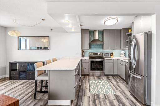 Modern kitchen with a large peninsula, seating for four, abundant cabinetry, and an open view into the living room.