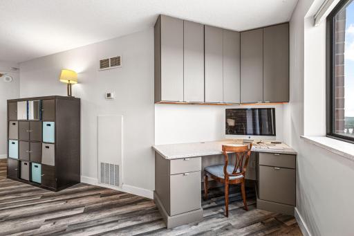 Dedicated workspace with built-in cabinetry, plank flooring, and a large window overlooking downtown St. Paul.