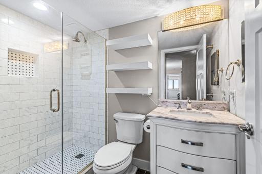 Updated bathroom featuring a glass-enclosed shower, modern vanity, built-in storage, and bright contemporary finishes.