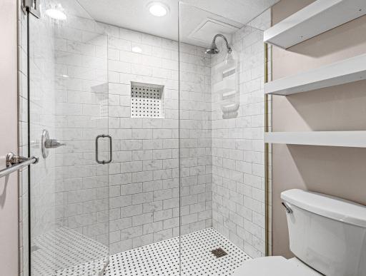 Glass-enclosed shower and built-in linen shelving add convenience to the updated bathroom.