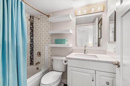 Guest bathroom featuring a tub and shower, modern vanity, generous storage, and bright neutral finishes.