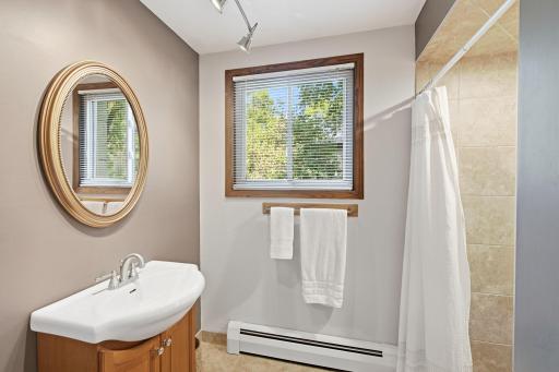 3/4 bathroom featuring a tiled showersurround, vanity and natural light.