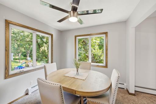 Bright dining area surrounded by large windows overlooking the lush, tree-filled setting.