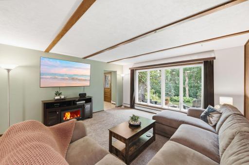 Large windows create a bright, comfortable gathering space with views of the mature trees outside.