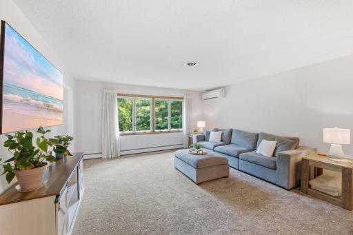 Spacious living room with large south-facing windows providing abundant natural light and views of the mature trees.