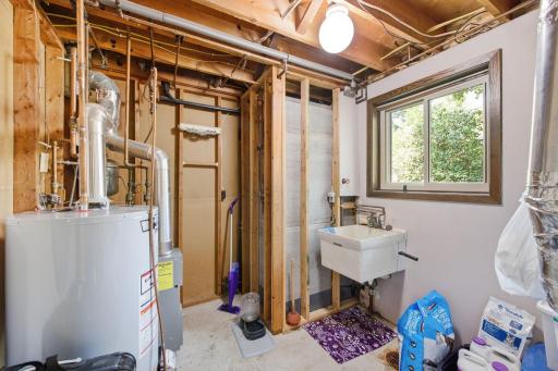 Utility area with mechanical systems, utility sink, window and additional storage space.