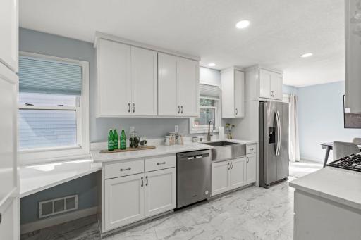 The updated kitchen features plenty of white cabinetry, quartz countertops, and stainless steel appliances.