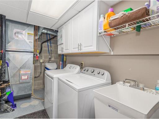Laundry area here with softener, washer is newer, utility sink and built in Cabinets.