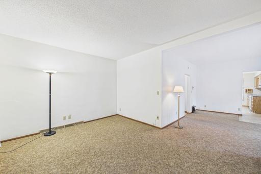 SPACIOUS main level living room! There are some hardwood floors under the carpet but the floorplan was changed over the years so there may be some plywood and patching.