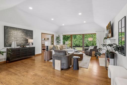 A wall of windows brings the beauty of the backyard into this inviting living room, while the fireplace creates a natural gathering spot for relaxed evenings.