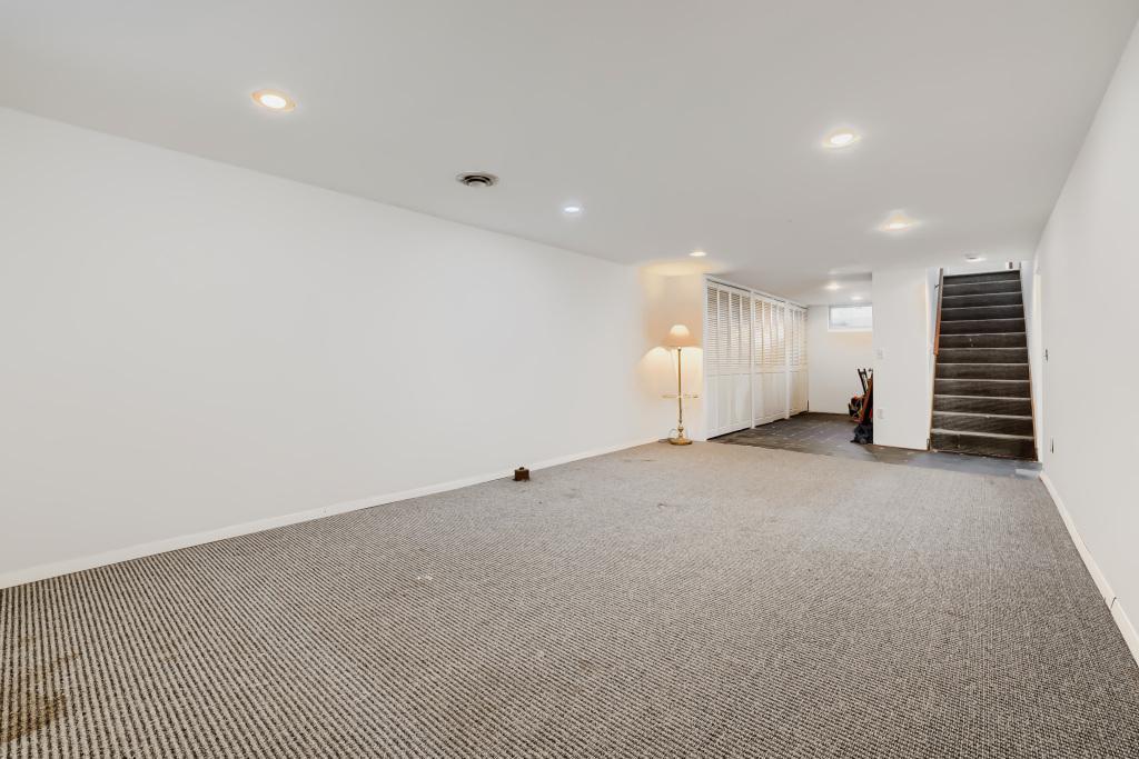 Lower level family room with recessed lights and work shop or home work area in back