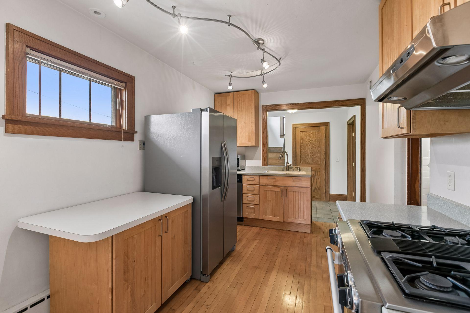 Modern kitchen with solid surface counters, stainless appliances, and wood cabinetry.