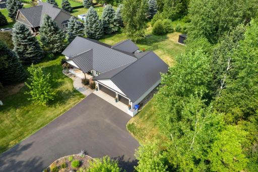 Mature tree coverage with asphalt driveway and fenced-in backyard